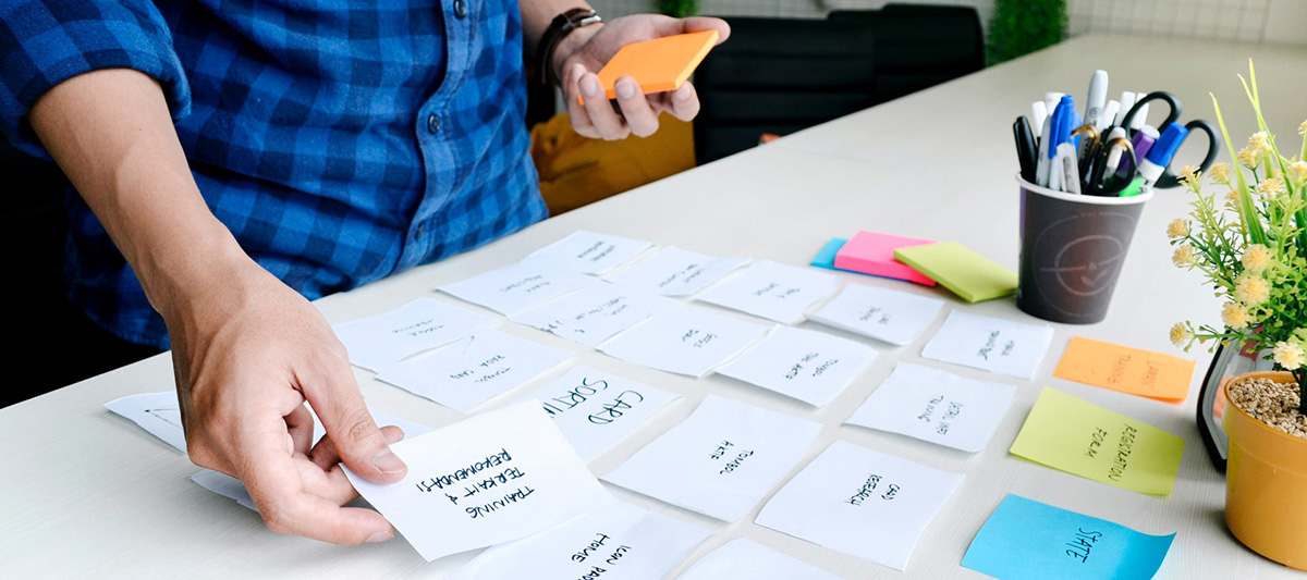 person arranging Post-it notes on a table